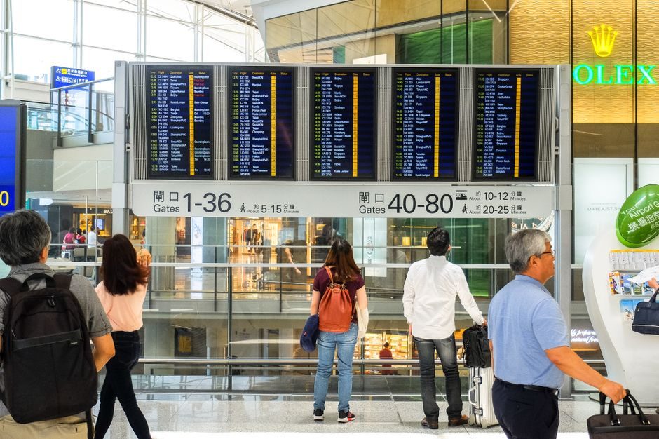 Voyageurs devant les écrans d'affichage des vols dans un hall d'aéroport