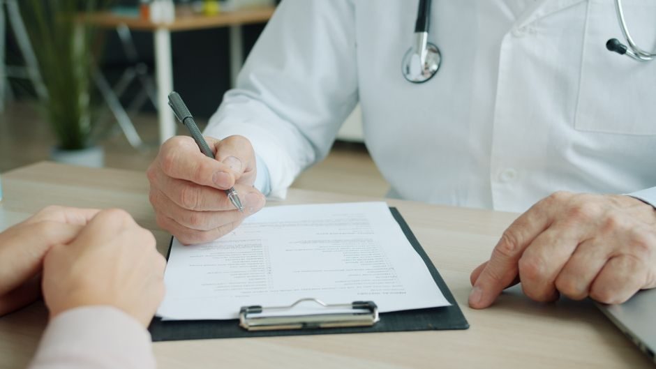Médecin remplissant une prescription médicale de transport avec son patient